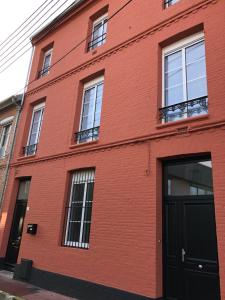 a red brick building with windows and a door at Maison Gabriel Appartement LUNE in Abbeville
