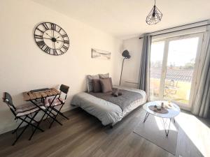 a living room with a bed and a clock on the wall at Charmant Studio in Talence