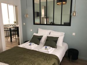 a bedroom with a bed with a mirror above it at Maison Gabriel Appartement LUNE in Abbeville