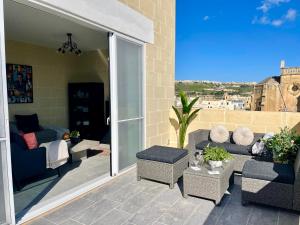 een patio met een bank en stoelen op een balkon bij Ta Phyllis - Apartments & Villas with Sunset & Sea Views in Għajnsielem