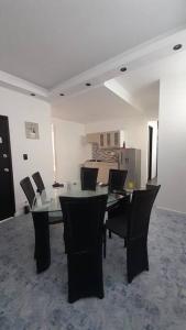 a dining room with a glass table and black chairs at Apartamento Las Palmas in Arauca