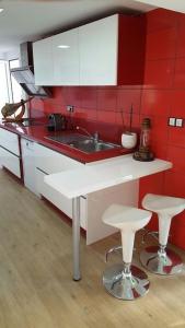 a kitchen with red walls and a sink and two stools at Casa con vistas al mar in Castelldefels