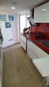 a kitchen with white cabinets and a red counter top at Casa con vistas al mar in Castelldefels