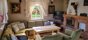 Cudodomek na Mazurach w Woszczelach koło Ełku في إوك: غرفة معيشة مع أريكة ومدفأة