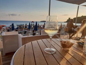 a glass of wine sitting on a table near the beach at Macinelle in Marina di Camerota