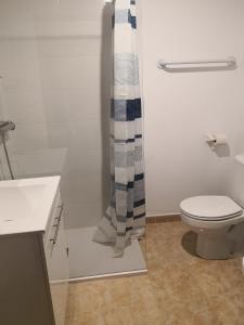 a bathroom with a toilet and a shower curtain at Finca La Pimienta in Pizarra