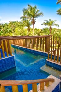 a swimming pool with a wooden fence and palm trees at Villaggio Orizzonte in Salvador