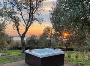 een hot tub in een tuin met een zonsondergang op de achtergrond bij Antico Casale Tiravento in Passignano sul Trasimeno