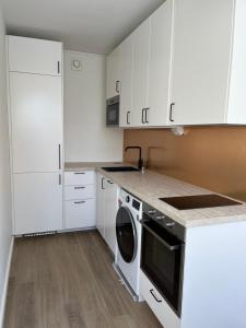 a kitchen with white cabinets and a dishwasher at Garden city studio in Espoo