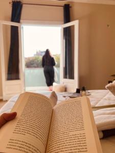 uma pessoa está a ler um livro numa cama em شقة هادئة في الزمالك no Cairo