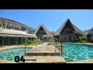 ein Haus mit einem Pool und einem Spielplatz in der Unterkunft 04 beach cottage malindi in Malindi