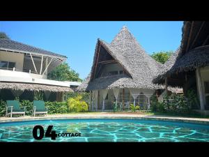 a resort with a swimming pool in front of a building at 04 beach cottage malindi in Malindi