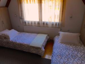 a bedroom with two beds and a window with curtains at The Lake House in Mikrolímni