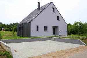 a large white barn with a black roof at Mali raj in Oštarije
