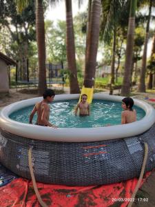 Tres chicos en una piscina en un resort en Bardia Kingfisher Resort, en Dhakela