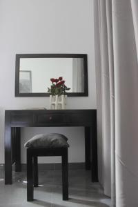 a black table with a mirror and a stool with a plant at Hoi An Viet House Homestay in Hoi An