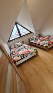 two beds in a attic room with a window at Dom pod Wroclawiem19 in Domasław