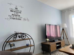 una sala de estar con TV y una bicicleta en la pared en Gîte Le Pont du Rameur en Pont-Rémy