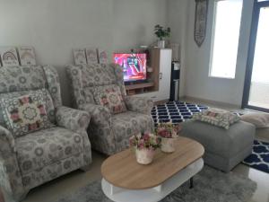 ein Wohnzimmer mit Sofas, einem Tisch und einem TV in der Unterkunft Adinda Syariah C-10 Bukit Gardenia Resort in Tarogong