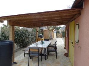 un patio con mesa y sillas bajo una pérgola de madera en Fischerhaus1940, en Le Barcarès