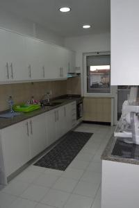 - une cuisine avec des placards blancs et un évier dans l'établissement Helena House, à Senhora da Hora