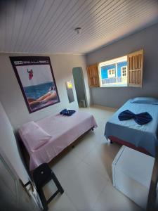 a room with two beds and a poster on the wall at Suítes good trip Itacare sem estacionamento in Itacaré