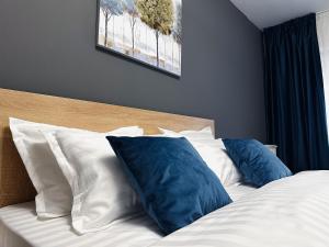 a bed with two blue pillows on top of it at AD Apartments in Cluj-Napoca