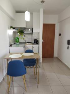 a kitchen with a wooden table and blue chairs at Cañada Suites in Córdoba