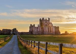 an old castle in a field with a fence at Ballyhack by the Sea in Arthurstown