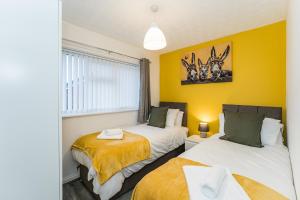 two beds in a room with yellow walls at AMAZING CONTRACTOR HOUSE 3 bedroom warm modern house free secure off road parking, wifi & sky sleep upto 8 guest s in Aintree