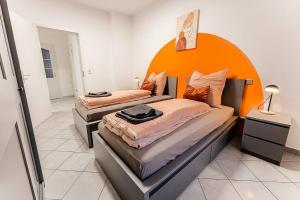2 Betten in einem Zimmer mit orangefarbenem Kopfteil in der Unterkunft Loft mit Billard-Tisch und PS4 in Wuppertal
