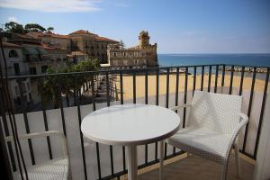 een tafel en stoelen op een balkon met uitzicht op het strand bij Palazzo Iaquinto in Santa Maria di Castellabate