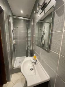 La salle de bains blanche est pourvue d'un lavabo et d'une douche. dans l'établissement Pokoje dominikańskie / Dominican rooms, à Wrocław
