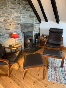 a living room with two chairs and a stone fireplace at Sea View ,Cottage2 Nc500 in Castletown