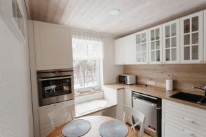 a kitchen with white cabinets and a table and a window at Vase Holiday Home in Tartu