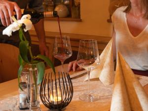 una mujer vertiendo vino en dos copas de vino en una mesa en Gasthof Rieder Stubn, en Ried im Oberinntal
