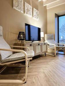 a living room with two chairs and a flat screen tv at Svencele Lounge Apartments in Svenele