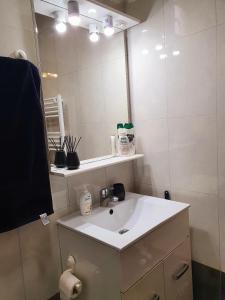 ein Badezimmer mit einem weißen Waschbecken und einem Spiegel in der Unterkunft Luk's Central Residence in Constanţa