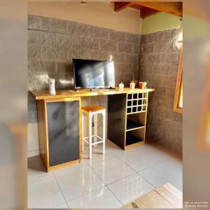 escritorio con TV y taburete en la habitación en Mora Tempo en Esquel