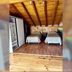 Habitación pequeña con 2 camas y techo de madera. en Mora Tempo en Esquel