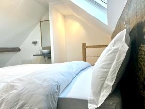 um quarto com uma cama com lençóis brancos e uma janela em Le Pampas - Duplex 4 pers - Lille - Tourcoing em Tourcoing