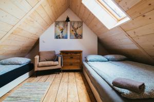 a attic bedroom with two beds and a chair at Apartamenty na Pastwisku in Szymbark