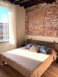een bed in een kamer met een bakstenen muur bij La finestra sul Museo del Mare in Genua