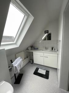 a white bathroom with a sink and a window at Apartment Düte in Erpen