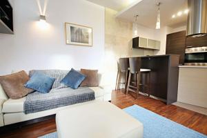 a living room with a white couch and a kitchen at Parkowy Apartament in Wrocław
