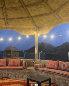 a group of benches on a roof with mountains in the background at The Fort Farm in Suḩaybah