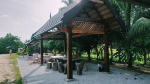 un pabellón con mesa, bancos y árboles en Sofea Homestay, en Batu Rakit