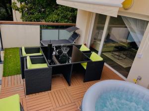 patio ze stołem, krzesłami i wanną z hydromasażem w obiekcie Superbe appartement cosy avec jacuzzi w mieście Francheville