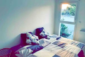 sypialnia z łóżkiem z poduszkami i oknem w obiekcie Superbe appartement cosy avec jacuzzi w mieście Francheville