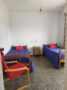 Cette chambre comprend 2 lits et une chaise. dans l'établissement Apartamento en primera línea con vista al mar, à Punta del Este